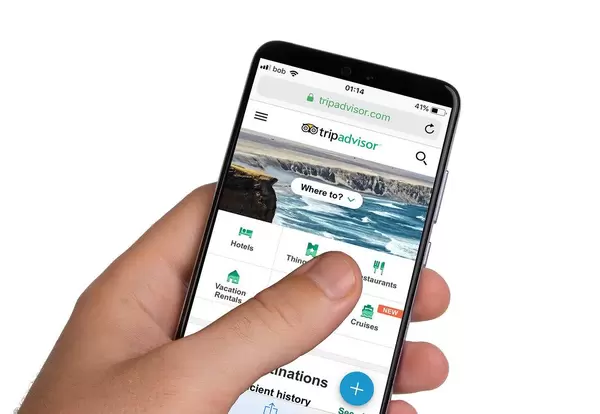 Male hands holding smartphone with an open Tripadvisor application