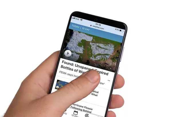 Male hands holding smartphone with an open Weather.com website