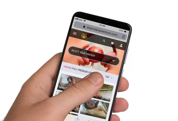 Male hands holding smartphone with an open Xhamster webiste