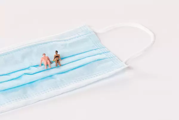 Man and woman in bath suit with medical face mask on white background