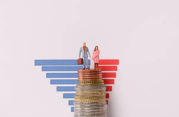 Man and woman standing on a stack of coins with bar graph