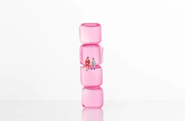 Man and women sitting on pink ice cubes