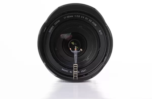 Man cleaning camera lens on white background