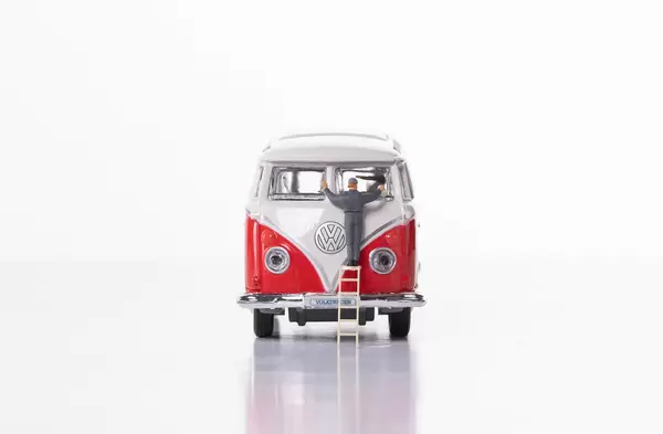 Man cleaning classic VW Camper van on white