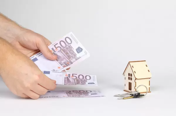 Man counting money with tiny wooden house and keys