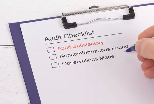 Man filling out Audit Checklist on clipboard