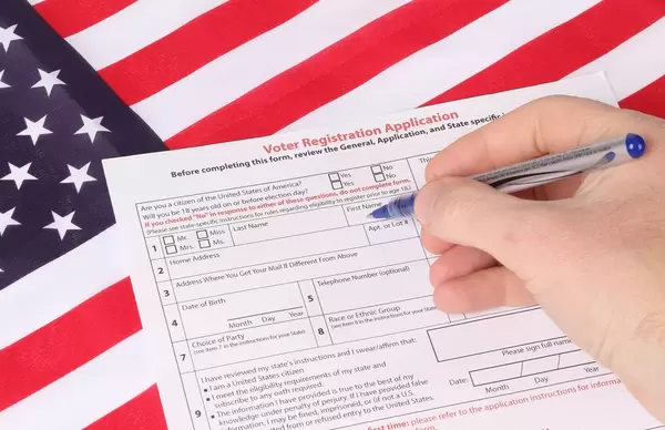 Man filling out Voter Registration Application with USA flag in background.jpg