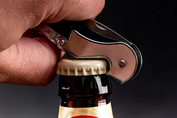 Man hand opens a bottle of beer