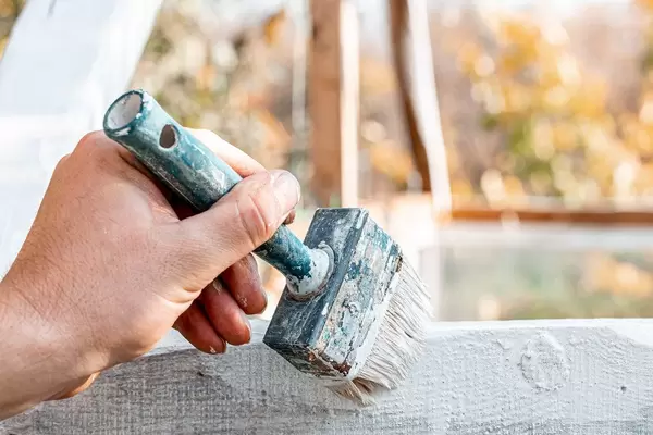 Man hand paints wooden surface with white paint (Flip 2019)