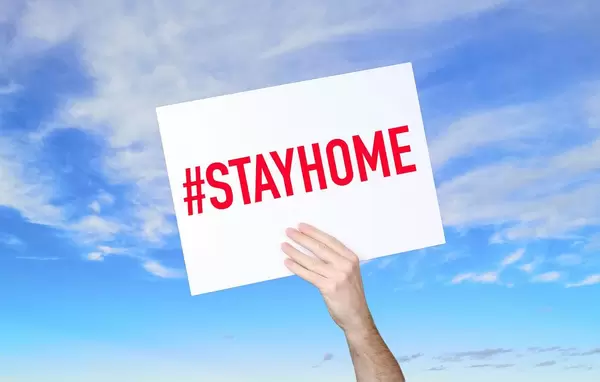 Man holding banner with #stayhome text with blue sky background