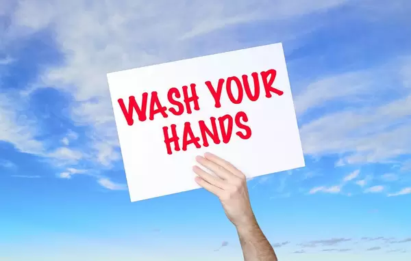 Man holding banner with Wash Your Hands text with blue sky background