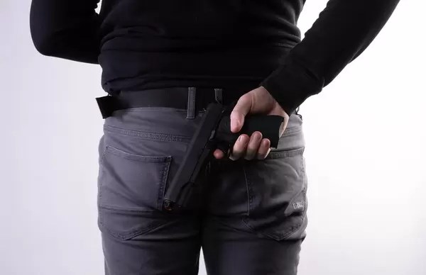 Man holding hidden hand gun in his hand