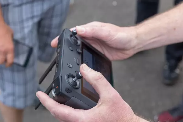 Man holds the DJI Mavic 2 Smart Controller to fly a drone outside