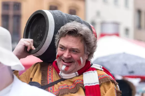Man in costume carries a black barrel on his shoulder