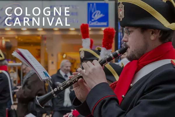 Man in guard uniform playing the clarinet, with attached sheet of music, during shrove Monday, next to picture title "Cologne Carnival"