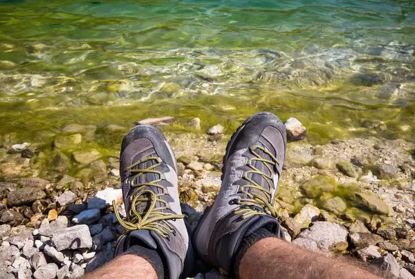 Man in hiking shoes sittng near the lake