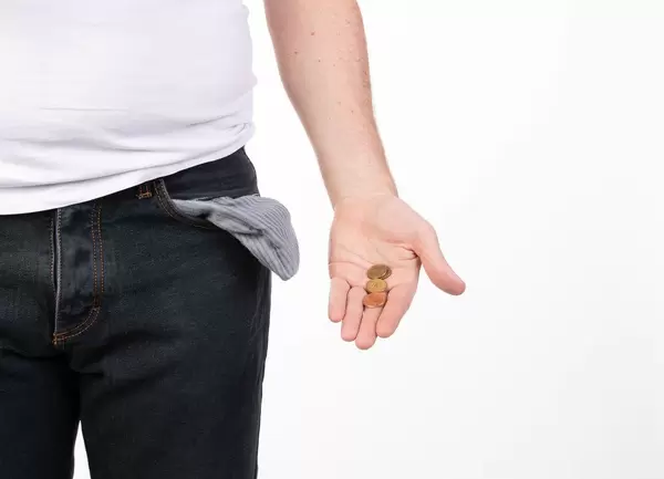 Man in jeans with empty pocket holding coins