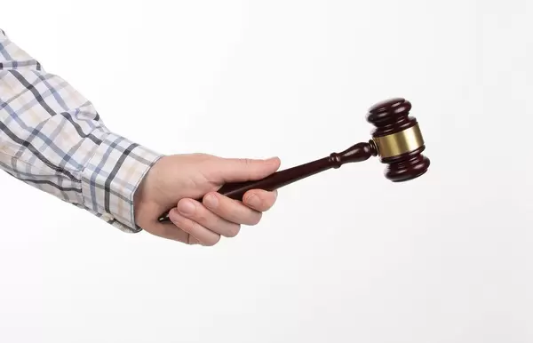 Man in shirt holding wooden judge gavel