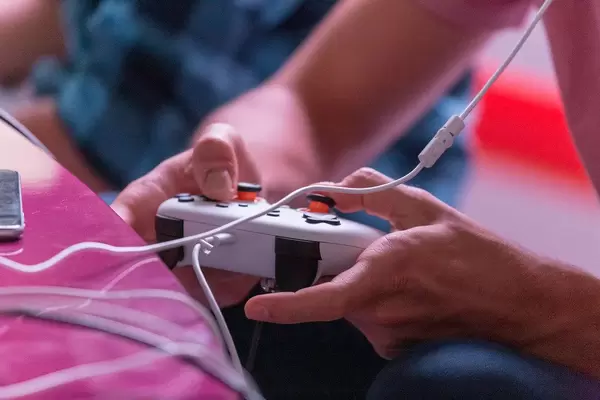 Man is pushing the buttons on a white Google Stadia Controller at the Gamescom game fair in Cologne