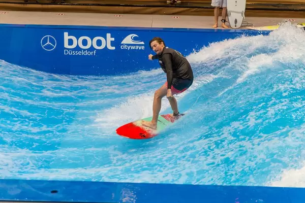 Man is surfing on citywave - standing wave at the exhibition boot Dusseldorf, Germany