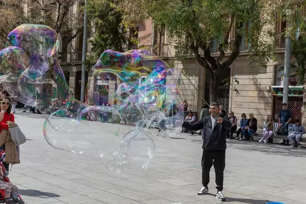 Man makes giant colourful soap bubbles in the city center of Barcelona