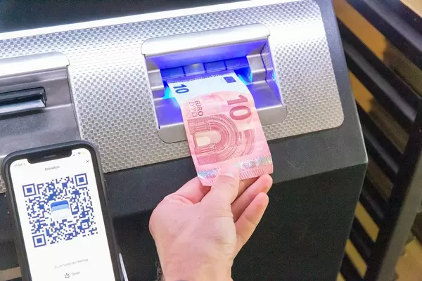 Man puts 10 Euro in a Bitcoin ATM, to transfer Bitcoins to his Smartphone via BlueWallet App