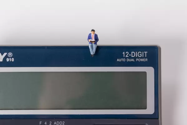 Man reading book while sitting on calculator