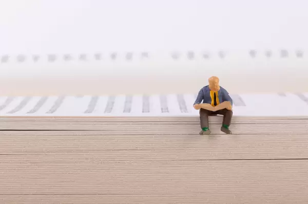 Man reading newspaper white sitting on a book