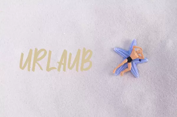 Man relaxing at sandy beach with Urlaub text