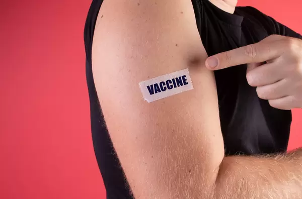 Man shows his sleeve with a bandage and Vaccine text