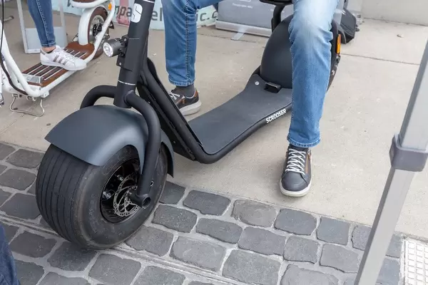 Man sits at a Scrooser emission-free electric scooter at the E-Cologne trade show for sustainable mobility