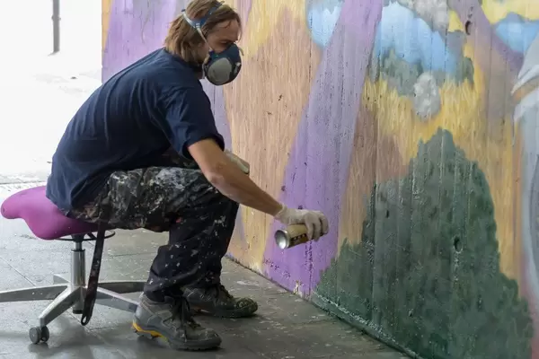 Man sitting on a chair and spraying graffiti