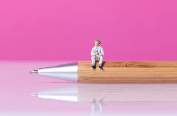 Man sitting on a wooden pen with pink bakground