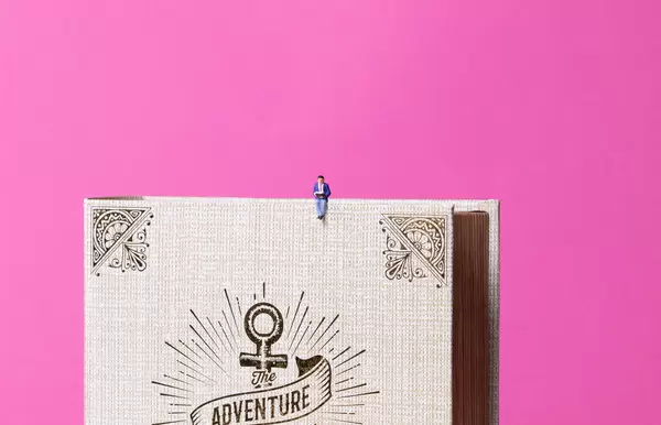 Man sitting on old book with pink background