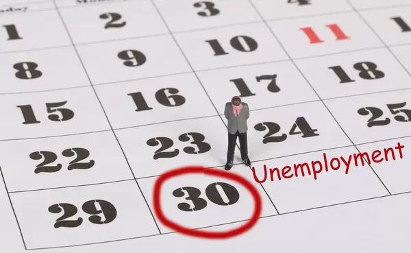 Man standing and looking at marked date with Unemployment text