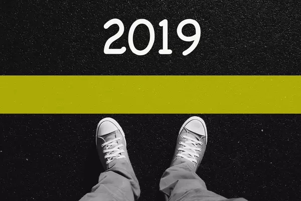 Man standing before text 2019 painted on asphalt