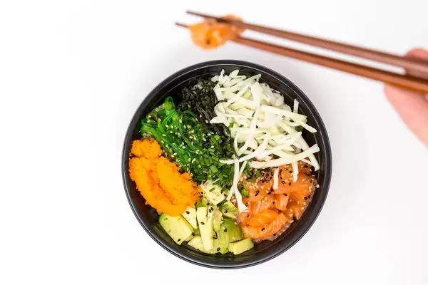 Man takes a piece of with chopsticks from the Poke Salmon Teriyaki Bowl