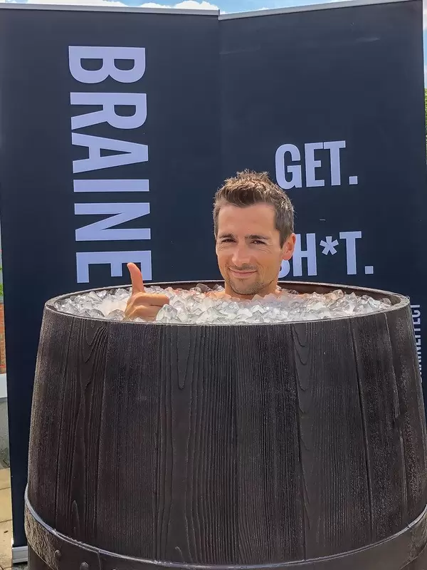 Man takes an ice bath in an old wooden barrel to regenerate himself after hard training and sports
