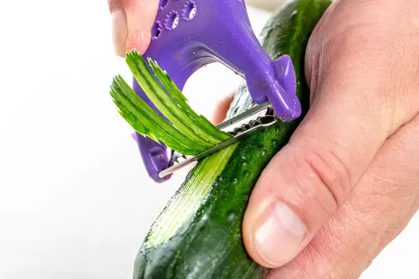 Man thin slices cucumber closeup