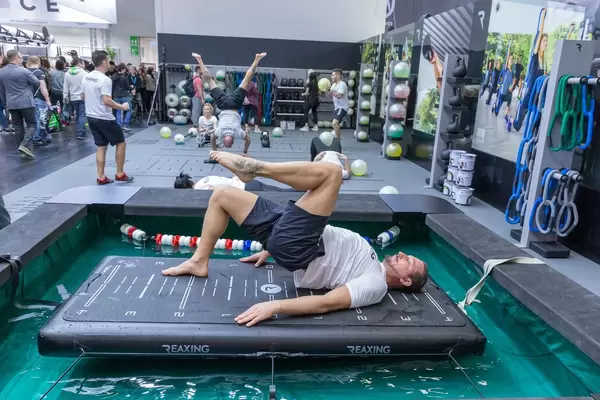 Man traint at a ReaxBoard and presents a new innovative way of neuromuscular training at Fibo fitness trade show in Cologne