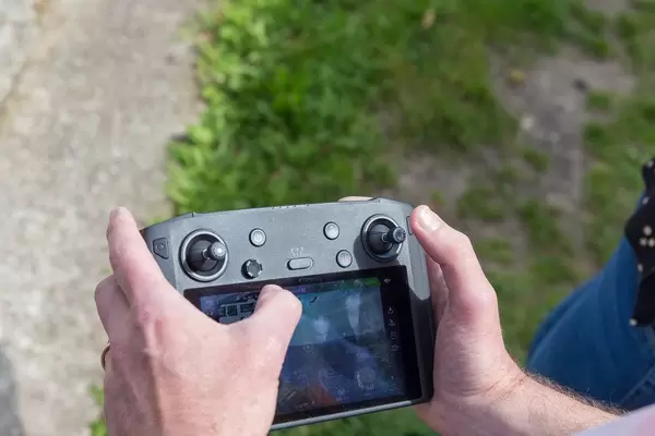 Man uses the black DJI Mavic 2 Smart Controller and drone remote control in the open field