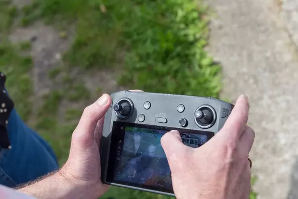 Man uses the DJI Mavic 2 Smart Controller to control the drone flight with the help of a large screen