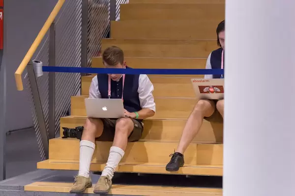 Man using Macbook sitting on stairs with barrier censoring his eyes