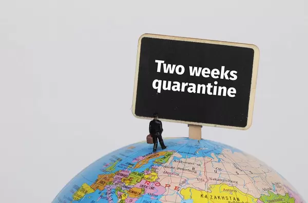 Man with a suitcase standing on globe with Two weeks quarantine sign