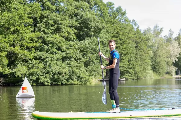 Man with paddle on a stand-up paddleboard, doing water sports on a lake in Finland