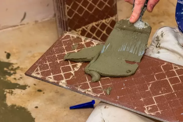 Man worker applies glue for laying tile