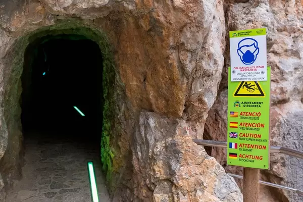 Mandatory face mask in the narrow, dark tunnel with footpath that leads to Sa Calobra beach (Mallorca)