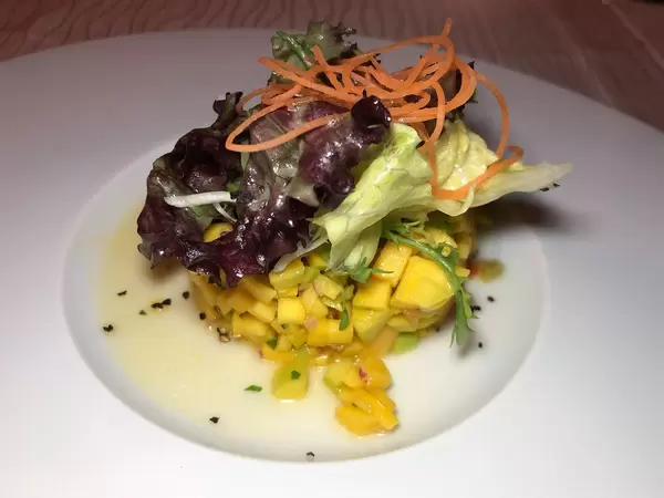 Mango-Salat angerichtet mit Möhrenstreifen auf weißem Teller