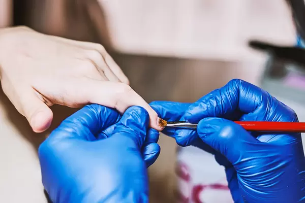 Manicure master applying cuticle cream on client nails