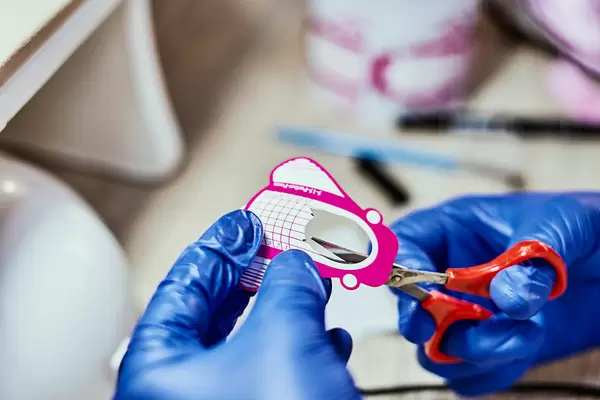 Manicurist cutting a fixative for nail extension